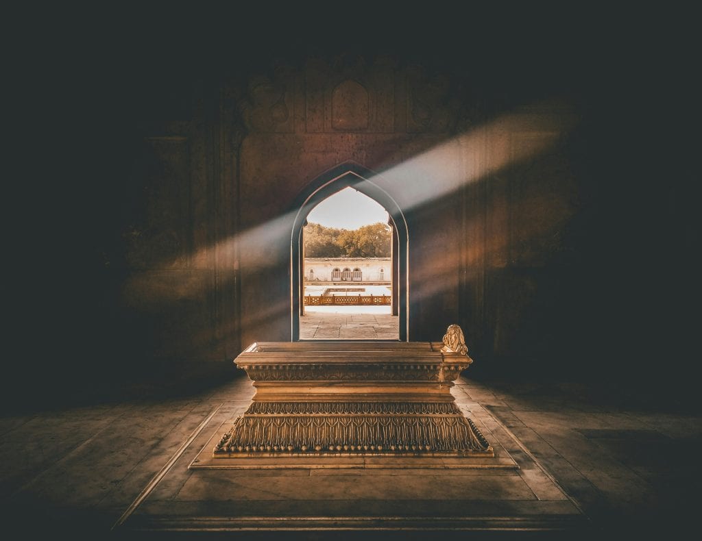 Beautiful tomb interior with a golden sarcophagus, illuminated by sunlight through an ornate archway.